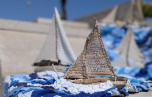 a crocheted boat on a wall against a blue sky